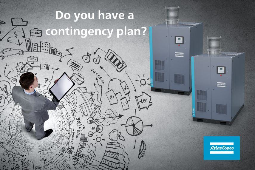 A man looking at a plan with two atlas copco compressors